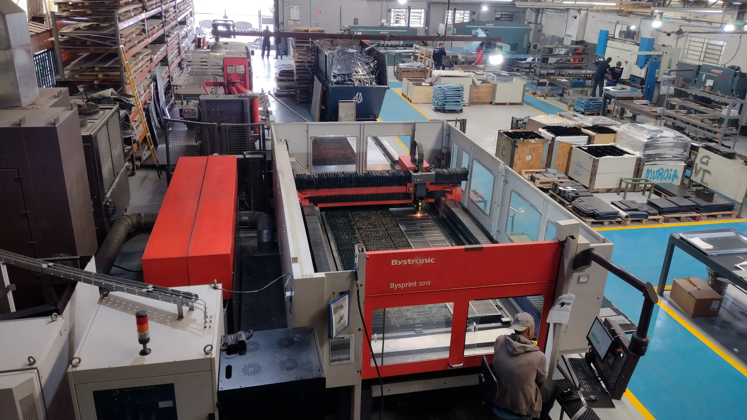 Área de produção da ArtMetal em Barueri, com máquina de corte a laser em operação e operador no painel de comando